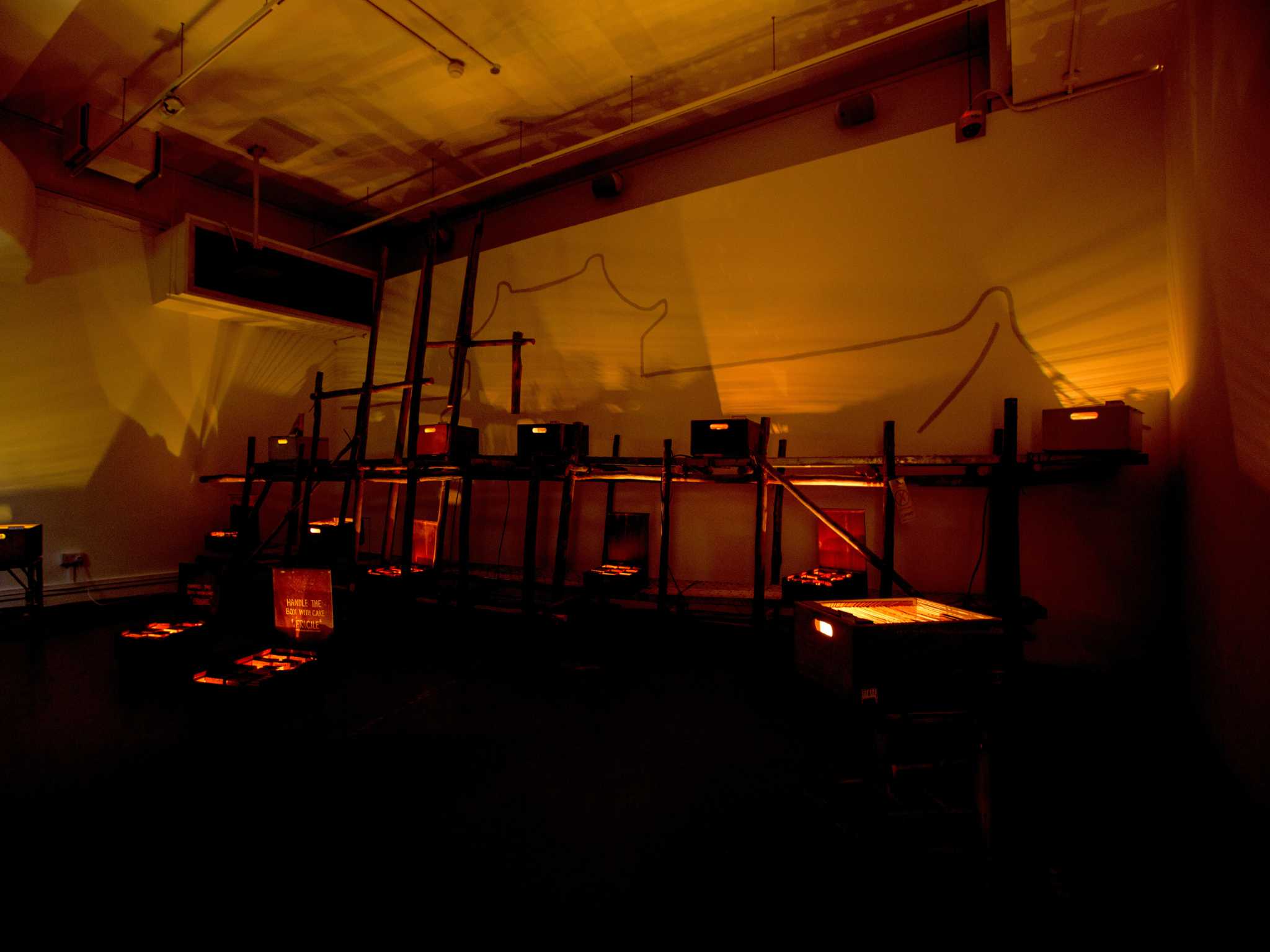 A dark room with screens set up on the floor and on a wooden structure. 